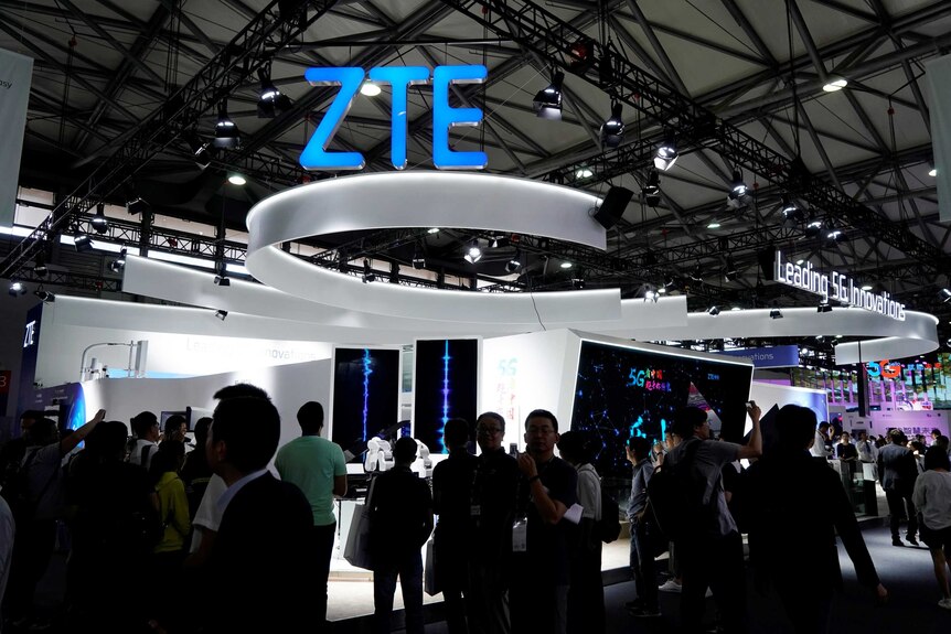 A ZTE sign is pictured at Mobile World Congress as a crowd of people walk around.