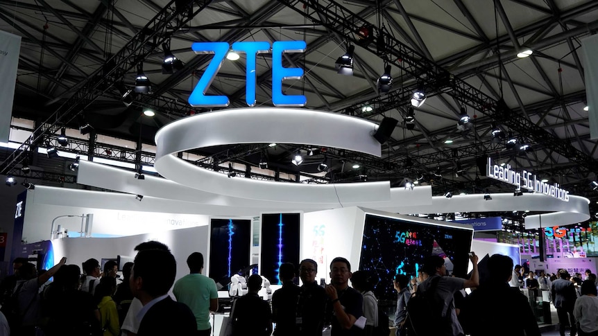 A ZTE sign is pictured at Mobile World Congress as a crowd of people walk around.