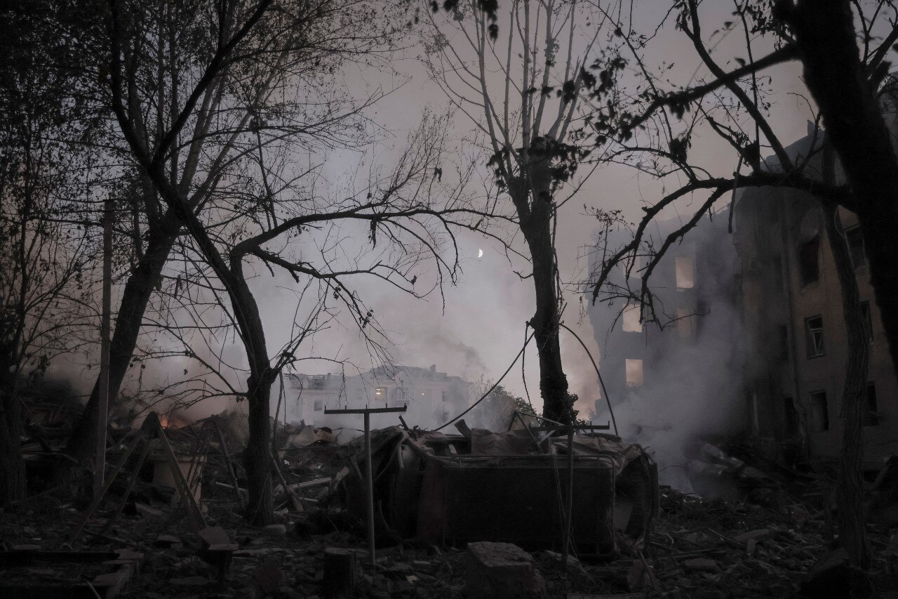 Smoke rises from several damaged buildings, seen in the early evening.