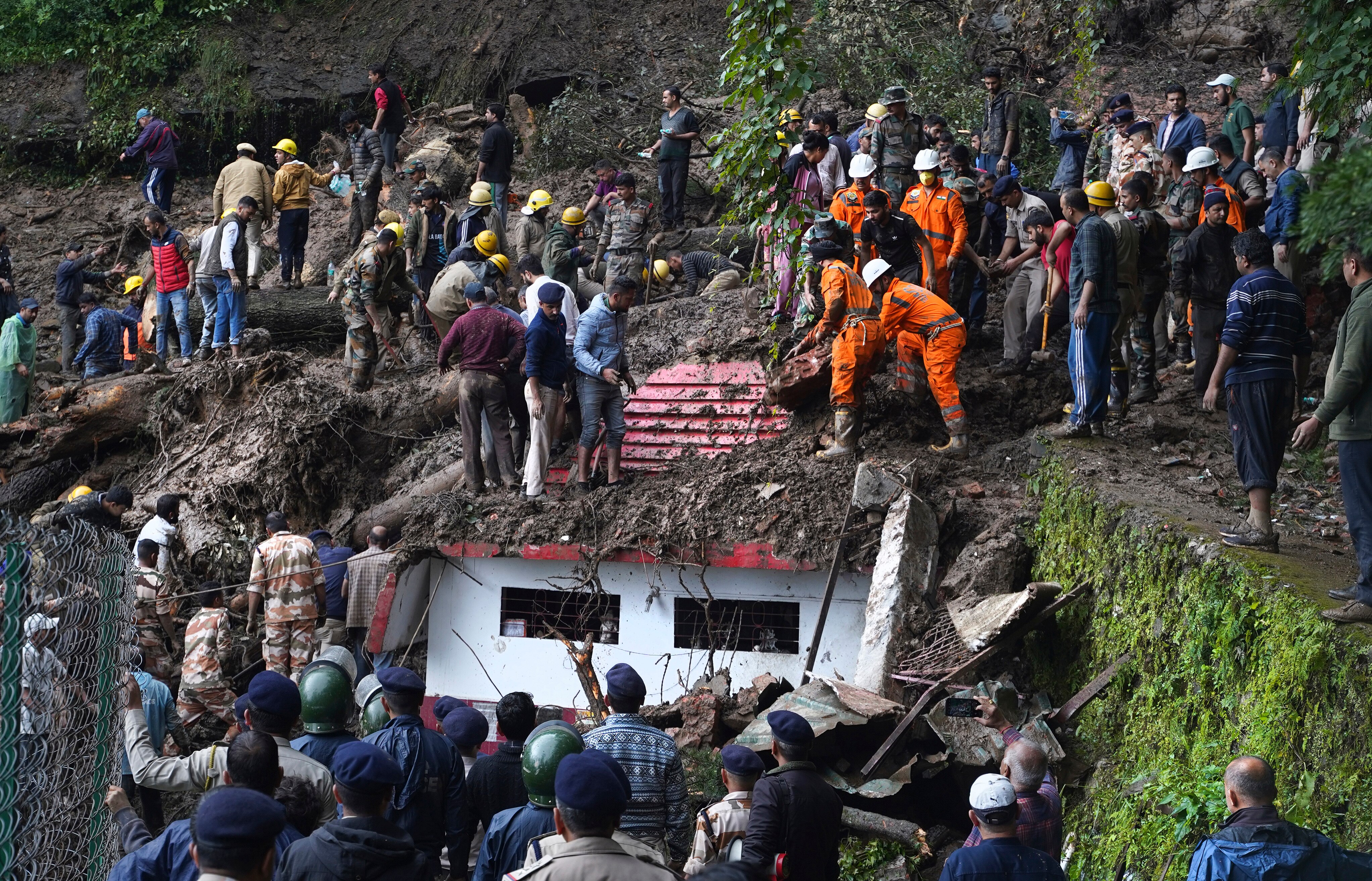 Crowds of rescuers remove mud and debris from a temple