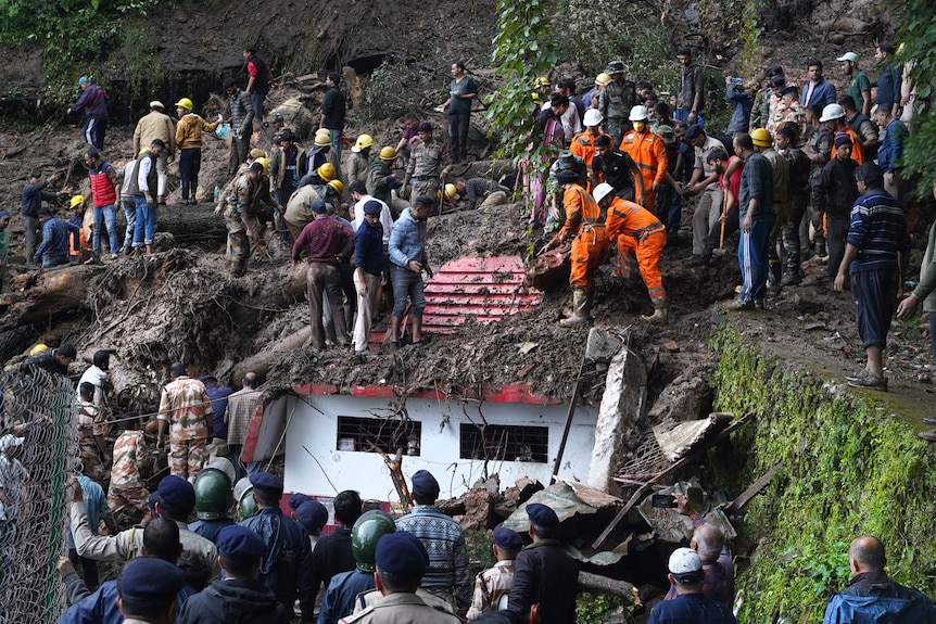 Crowds of rescuers remove mud and debris from a temple