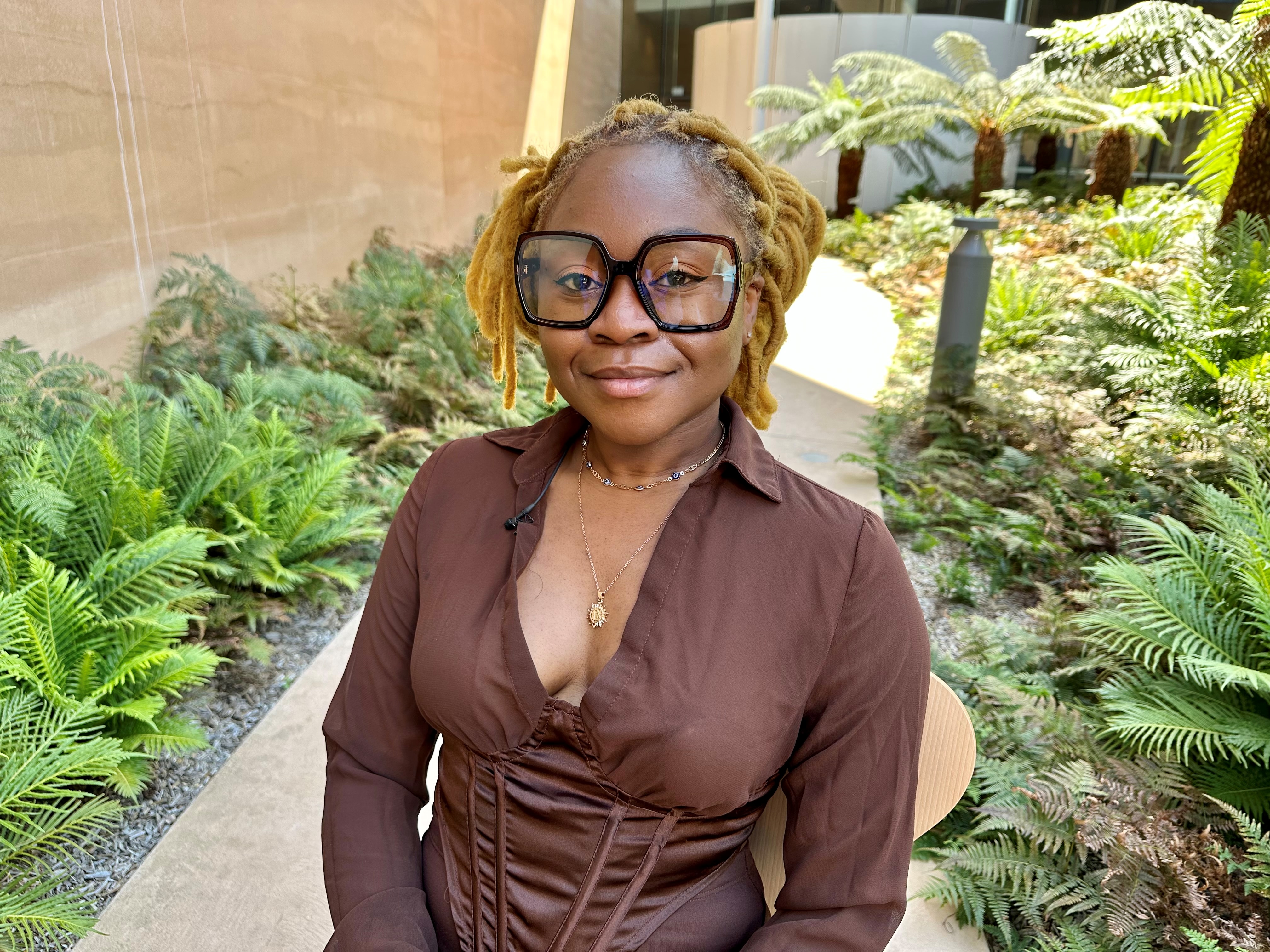 a female artist wearing wide rimmed glassed looks at the camera outdoors