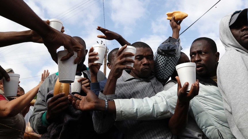 Haitian migrants receive food and drinks from volunteers as they wait in line at a Mexican immigration agency in Tijuana.