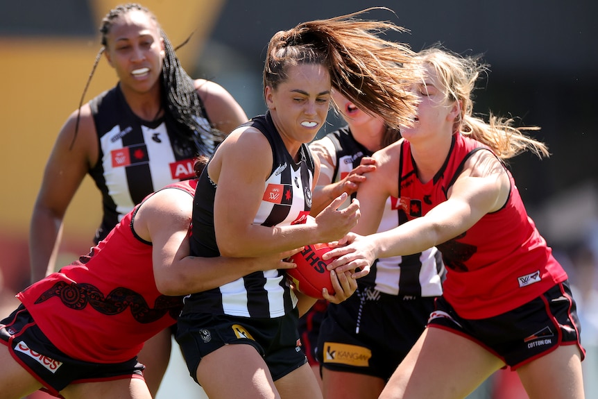 A Collingwood AFLW player with the ball against Essendon.
