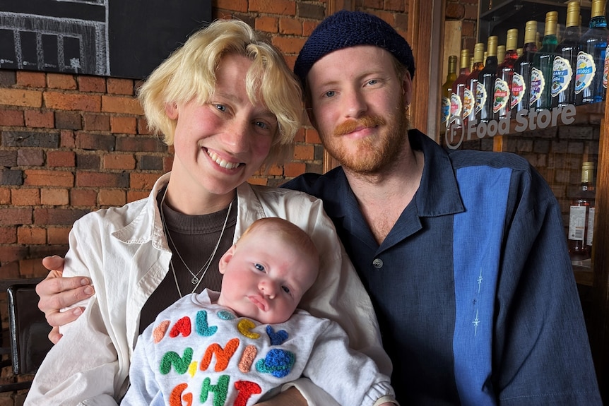 Bella Ainsworth and Mitch Barrett with their three-month-old son, Saf, sit at a cafe in Shepparton.