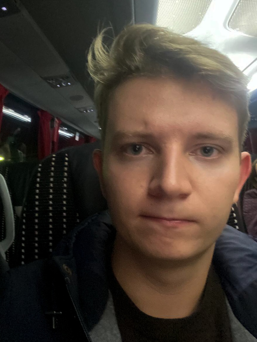 A young man takes a selfie on a bus