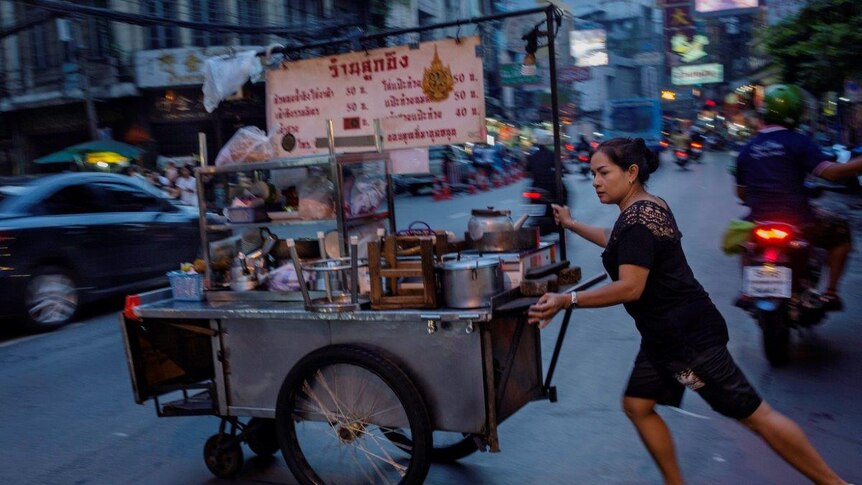 Street vendor pushes cart across the street