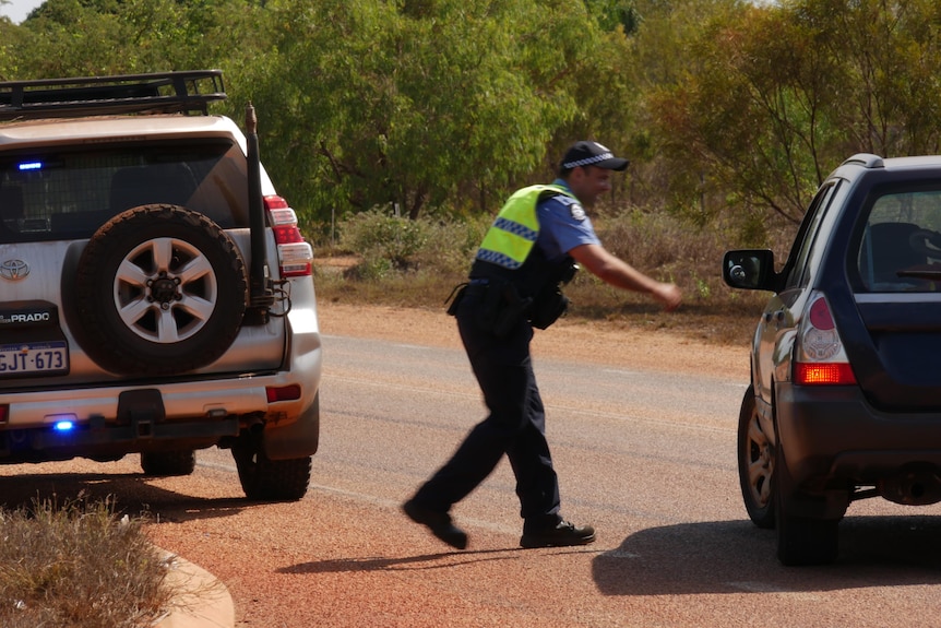 Image of a police officer approaching a car to search it.