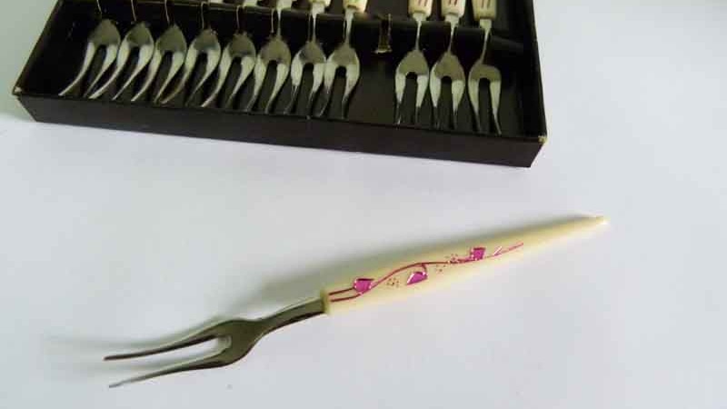 A fork with two prongs on a table, flanked by a box of identical forks.