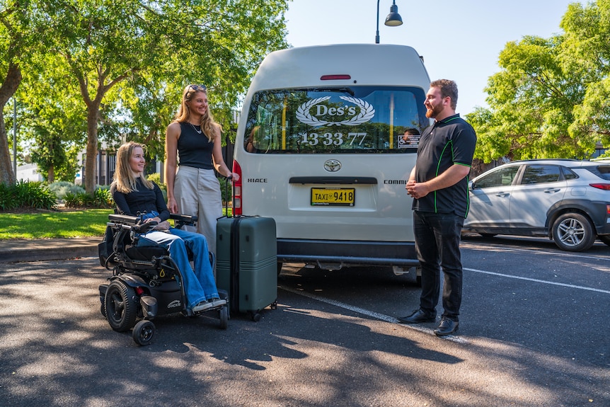 two young women, one in a wheel chair being picked up by an access taxi