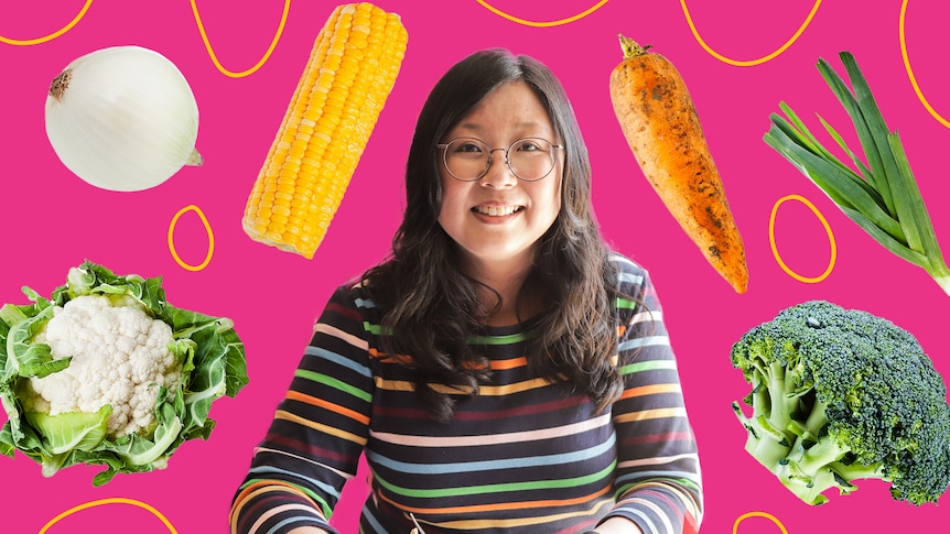 Jennifer Wong surrounded by vegetables like cauliflower, corn, onion, sweet potato, spring onion, broccoli.