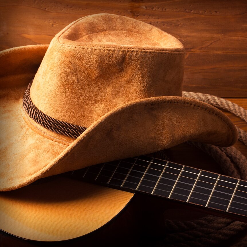 A farmer's felt hat sitting on top of a guitar.