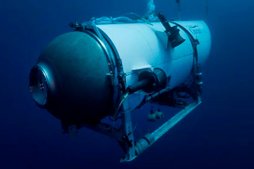 A cylindrical white metal underwater craft floats in a dark blue mass of water.