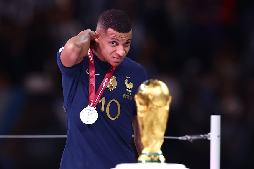 Kylian Mbappe looks at the World Cup trophy