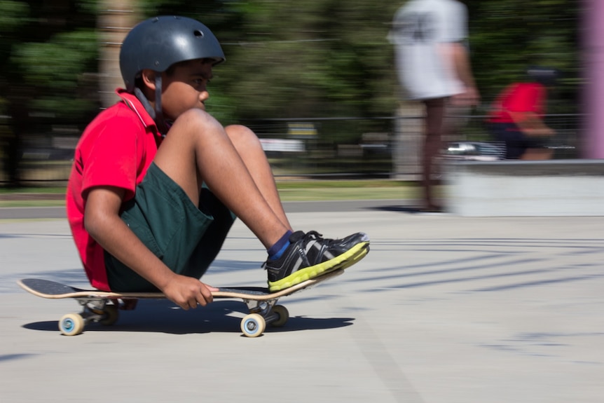 Boy rides his skateboard sitting down