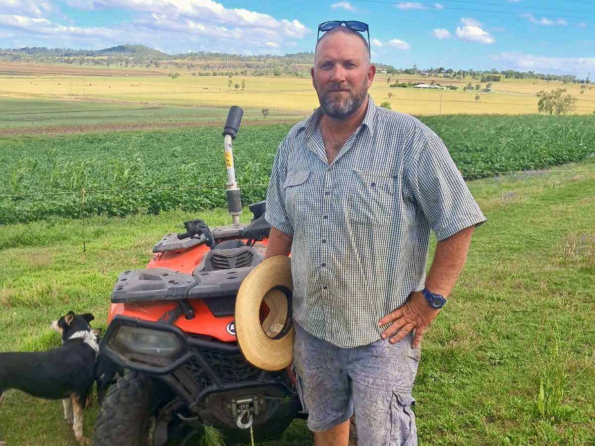 Un granjero cerca de su vehículo todo terreno en un prado.