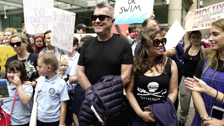 man in sunglasses with young people with protest signs