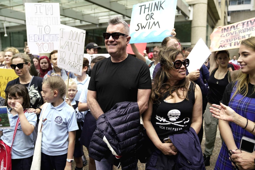 man in sunglasses with young people with protest signs