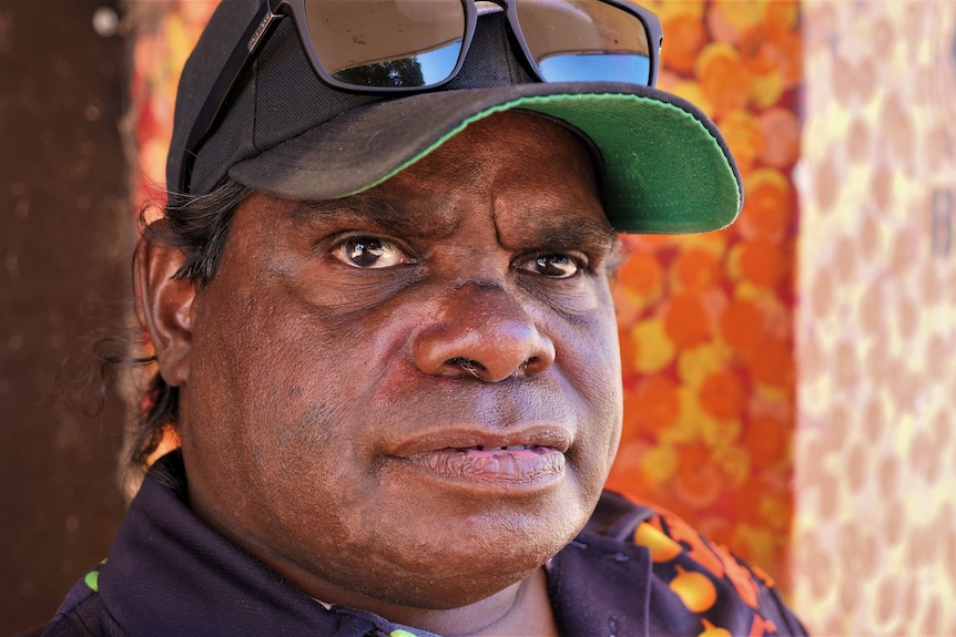 Close up of Aboriginal man with Aboriginal street art in the background.