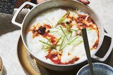 A hand cradling a bowl of fish congee