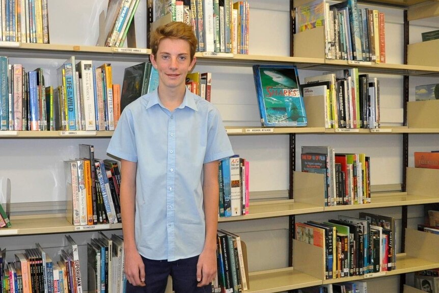 Riley Hayden stands in front of a book case at Nambucca High School.