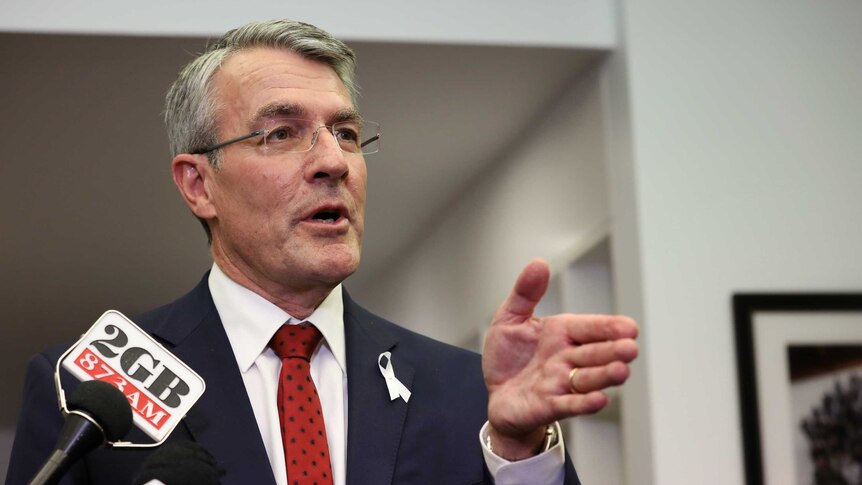 Mark Dreyfus, with a 2GB microphone hovering close to his face, gestures with his left hand while talking to reporters.
