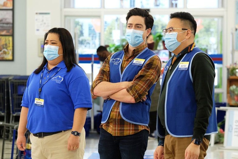 Three store employees in blue uniforms wear masks while at work. 