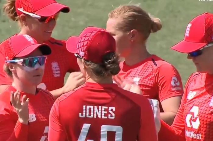 England cricket players talk to each other wearing red cricket players
