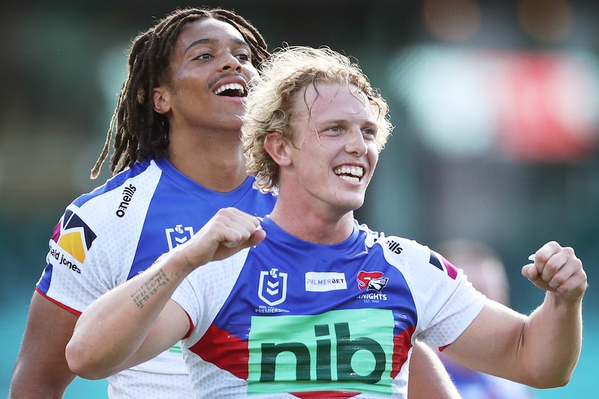 Two Newcastle Knights NRL players celebrate a try against Sydney Roosters.