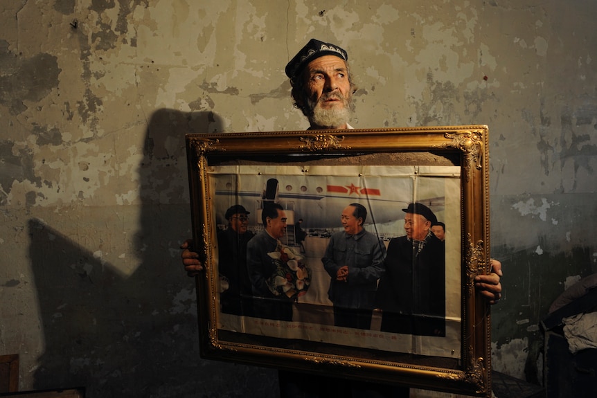 A Uyghur man holding a painting. 