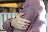 A woman clutches her left arm