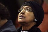 Winnie Madikizela-Mandela in black clothes looks above her with a somber expression