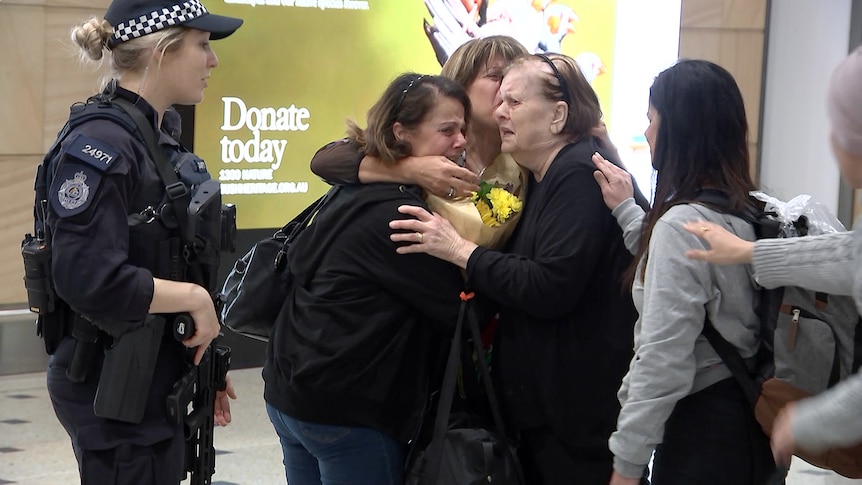 a group of palestinian women hug at the arrivals gate at sydney aiport