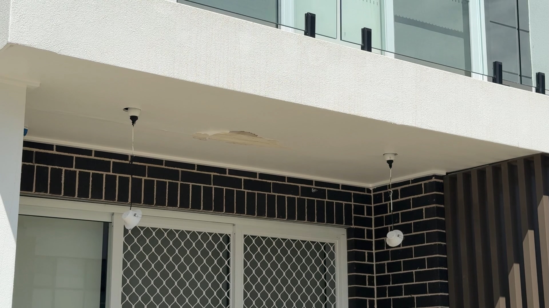 image of outdoor lights dangling from wires under balcony