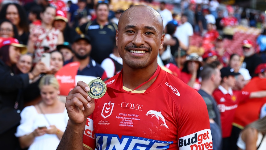 A man holds up a medal after winning man of the match