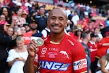 A man holds up a medal after winning man of the match