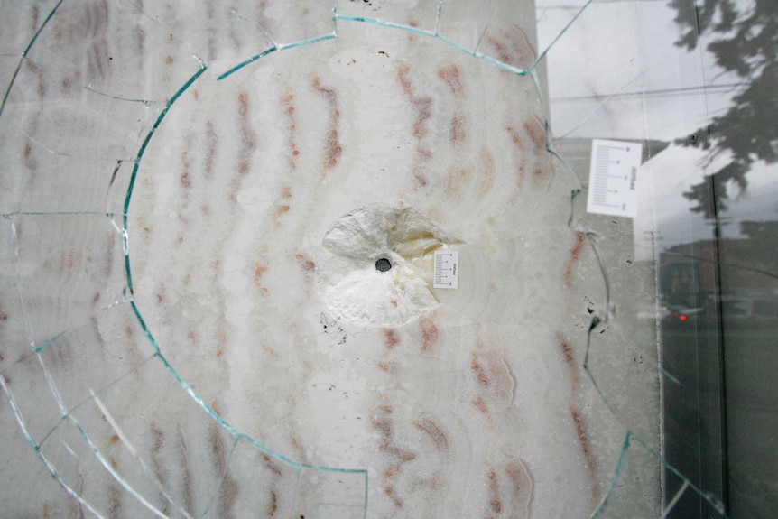 A bullet hole is seen in a window of the American Civic Association building