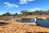 A young girl beside a desert waterhole.