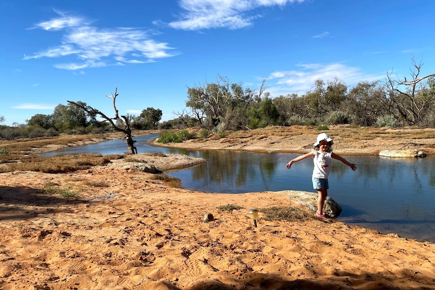 A young girl beside a desert waterhole.