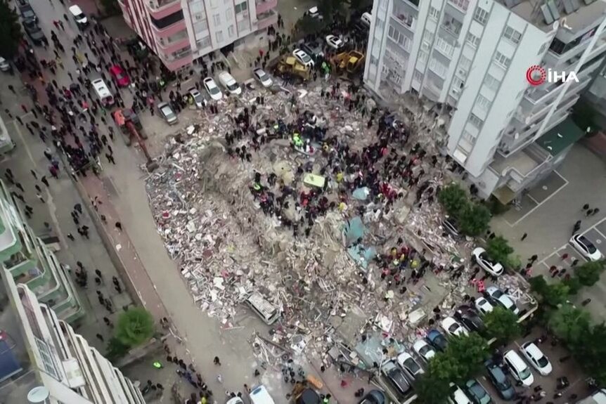 an aerial shot of people sifting through rubble.