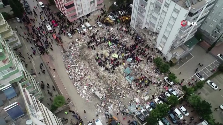 an aerial shot of people sifting through rubble.