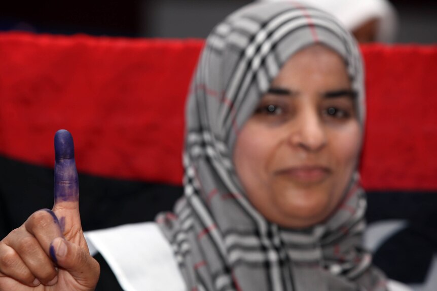 A Libyan woman shows her ink-stained finger after voting