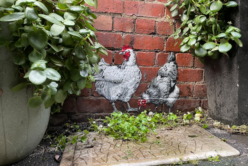 A closeup of a street with painted chickens and plants.