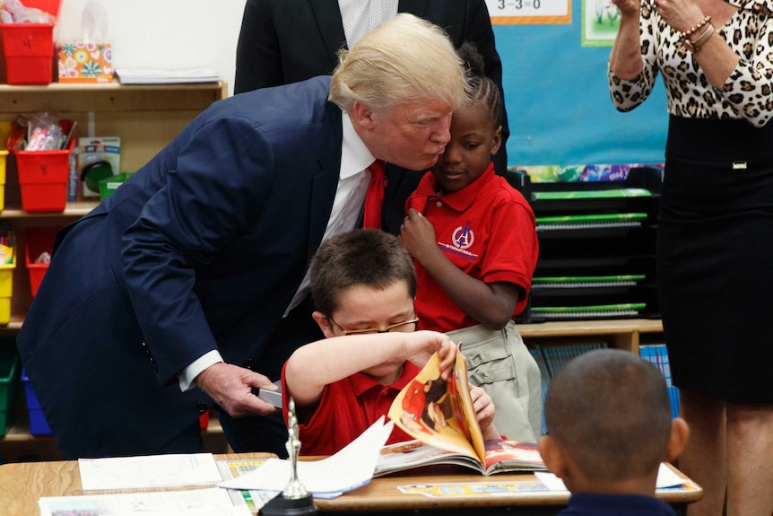 Donald Trump attempts to kiss a child on the cheek but misses.