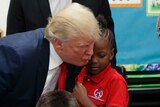 Donald Trump attempts to kiss a child on the cheek but misses.
