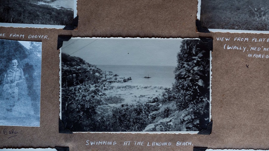 An old black and white photo with white crimped edges in an old photo album, showing a beach