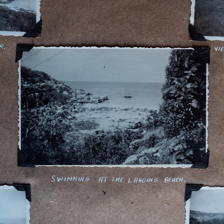 An old black and white photo with white crimped edges in an old photo album, showing a beach