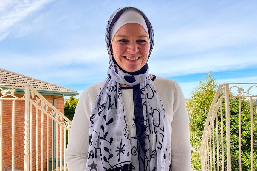 A woman wearing a headscarf and smiling to camera