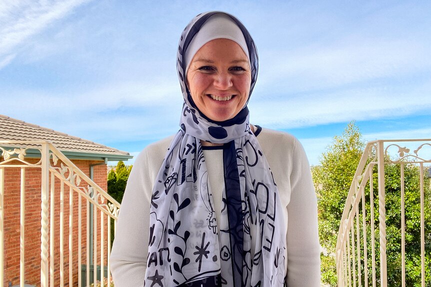 A woman wearing a headscarf and smiling to camera