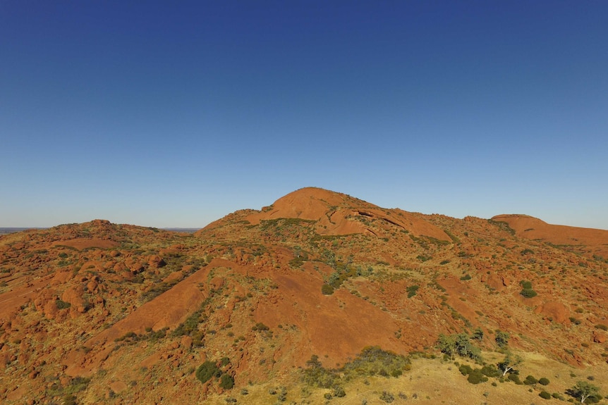 A rocky red terrain against a clear blue sky